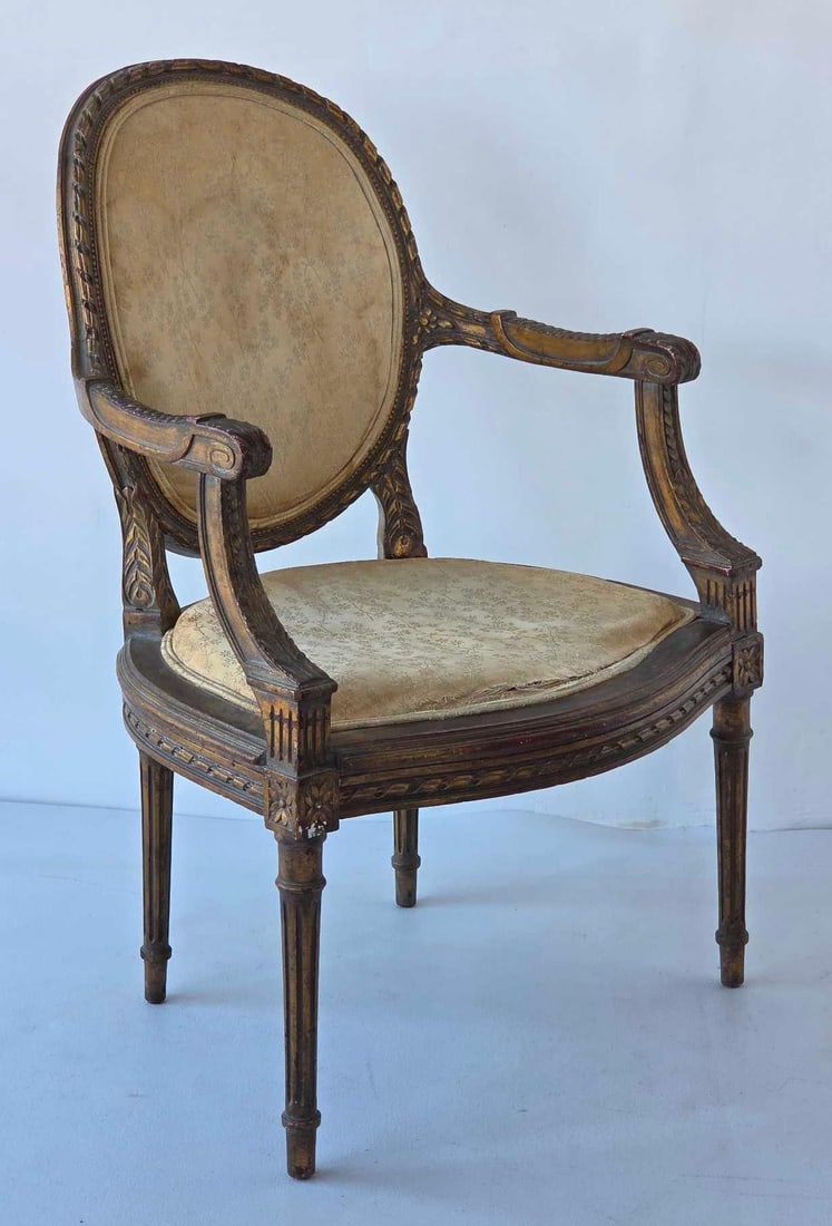 FRENCH LOUIS XVI STYLE CARVED GILTWOOD FAUTEUIL ARMCHAIR: *Classic oval-back open armchair with laurel leaf and ribbon carvings, fluted tapered legs, and floral damask upholstery. Approximate Dimensions: 36.5"h x 23.5"w x 24"d Artist or Maker: