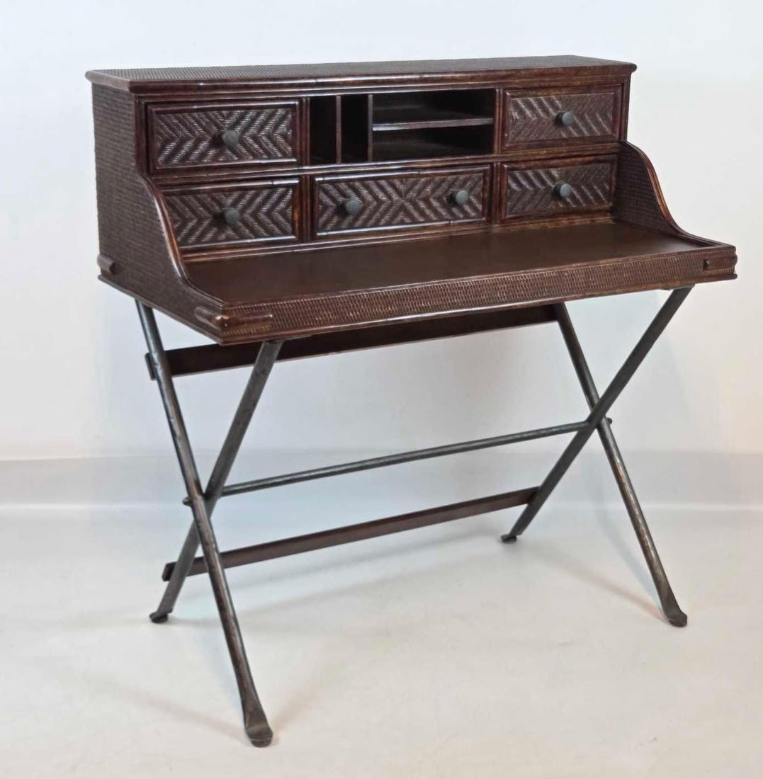 CAMPAIGN STYLE FAUX BAMBOO WICKER DESK ON STAND: Dark stained faux bamboo and herringbone wicker campaign-style desk on folding X-base stand. Approximate Dimensions: 42.5"h x 42"w x 21.75"d Artist or Maker: Unknown Provenance: