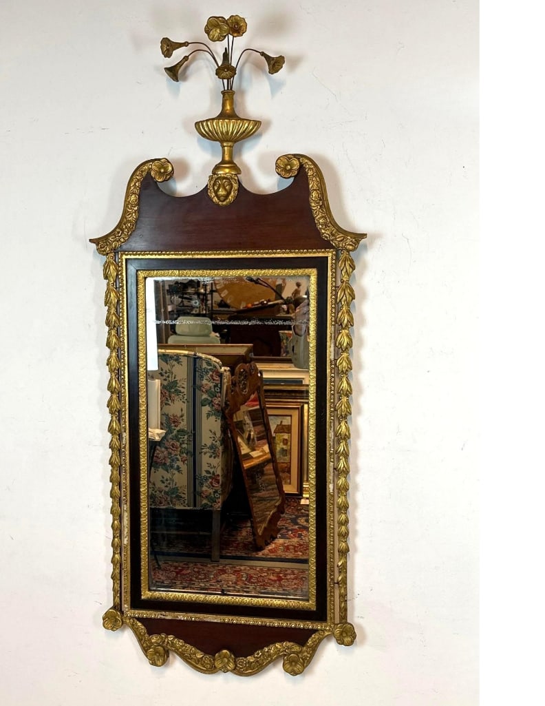 ANTIQUE MAHOGANY AND GILTWOOD CHIPPENDALE STYLE PIER MIRROR: Impressive 19th-century neoclassical wall mirror featuring a broken pediment top with a central floral urn finial and a lion masque detail. Approximate Dimensions: Approximate dimensions: 25.5”W