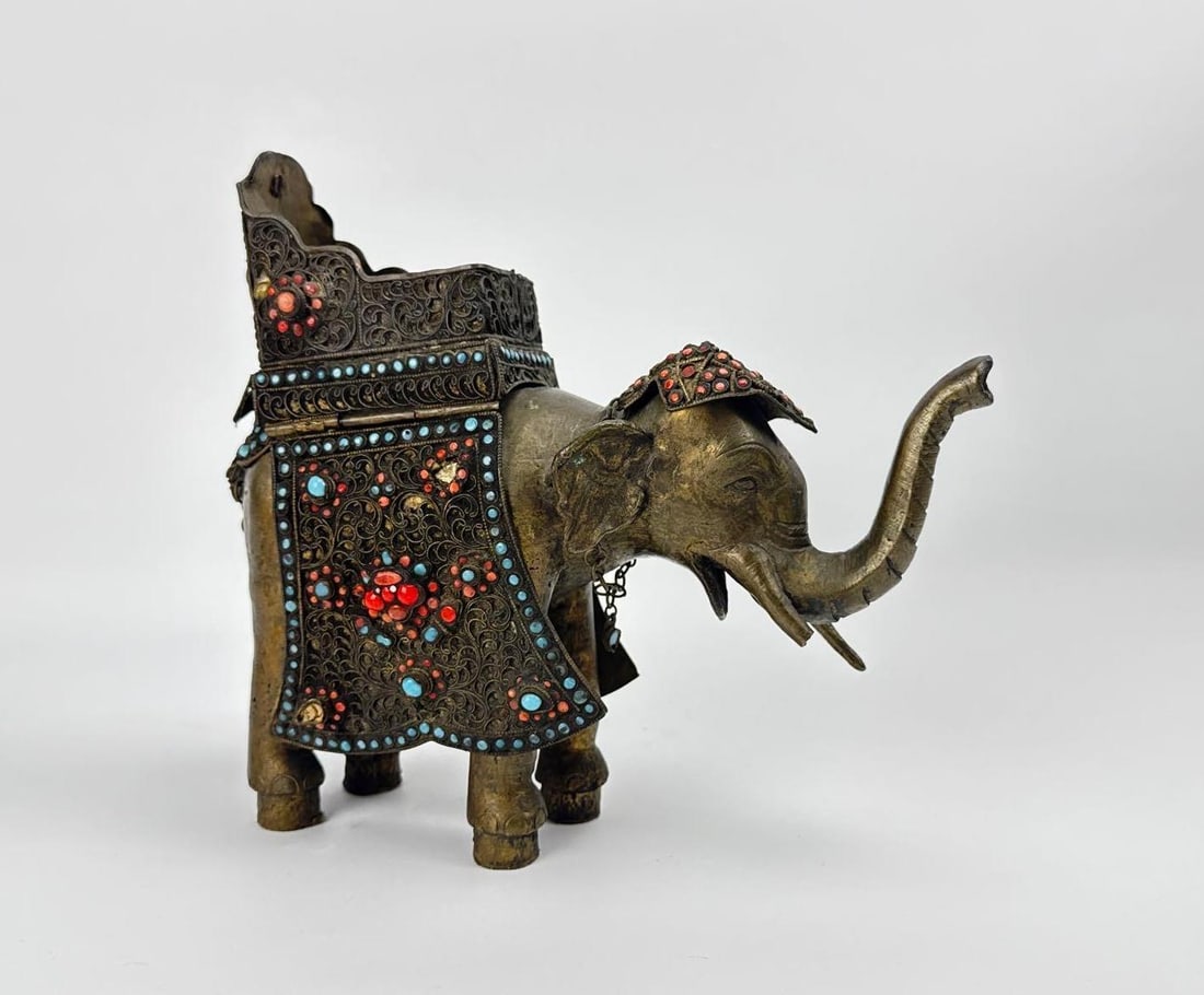 CHINESE SILVER-PLATED FILIGREE ELEPHANT WITH TURQUOISE AND CORAL CABOCHONS: Intricate silver over brass wirework filigree elephant censer with coral and turquoise style stones and removable howdah lid Approximate Dimensions: 9”h x 3.25”w x 10.25”d Artist or