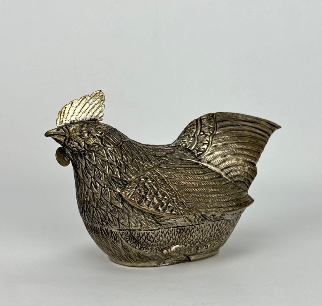 CAMBODIAN KHMER REPOUSSÉ SILVER HEN FIGURAL BETEL NUT BOX: Hand-chased silver figural hen shaped container with detailed feather plumage and traditional scrollwork. Approximate Dimensions: 4”h x 6”w x 3”d Weight: 3.195 0zt Artist or Maker: