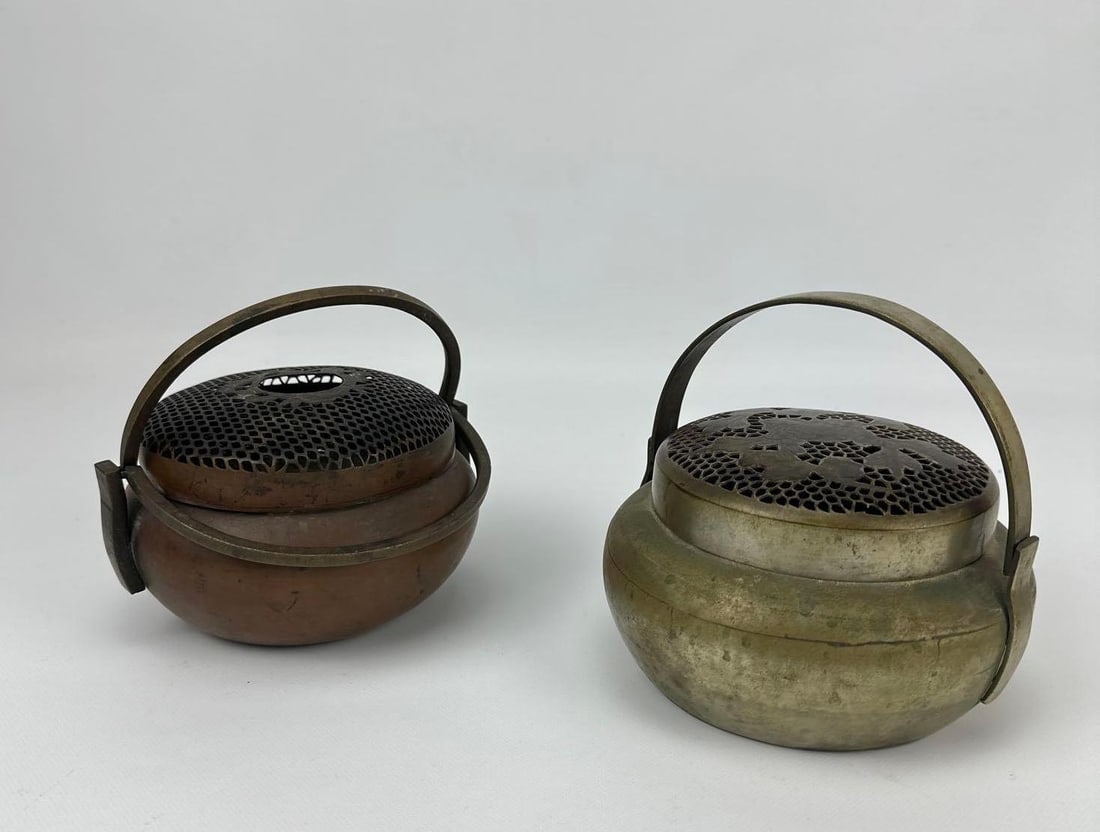 PAIR OF ANTIQUE JAPANESE BRONZE AND BRASS HAND WARMER INCENSE BURNERS: Set of squat circular vessels with swing handles and pierced honeycomb lids. Approximate Dimensions: 4” x 6”’dia Artist or Maker: Unknown Provenance: From a Bridgehampton