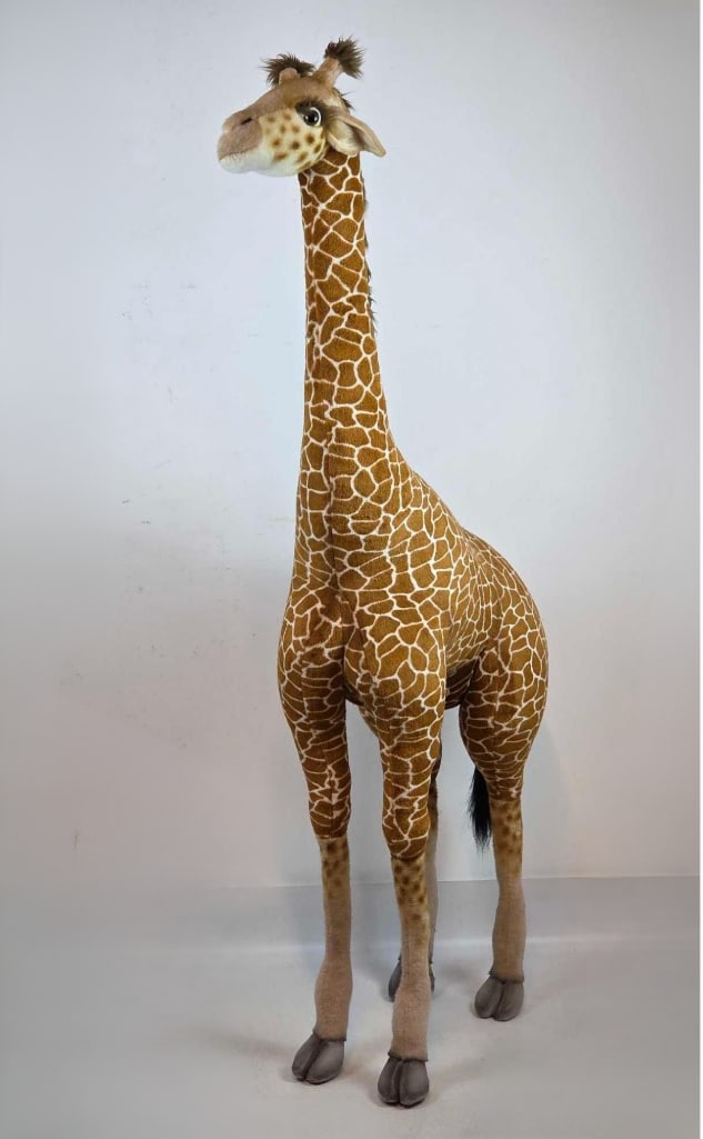 LIFESIZE PLUSH GIRAFFE STUDIO FIGURE BY HANSA: Large scale plush giraffe floor sculpture with handcrafted detail. Approximate Dimensions: 64"h x 35"w x 13"d Artist or Maker: Hansa Provenance: From a New York Collector