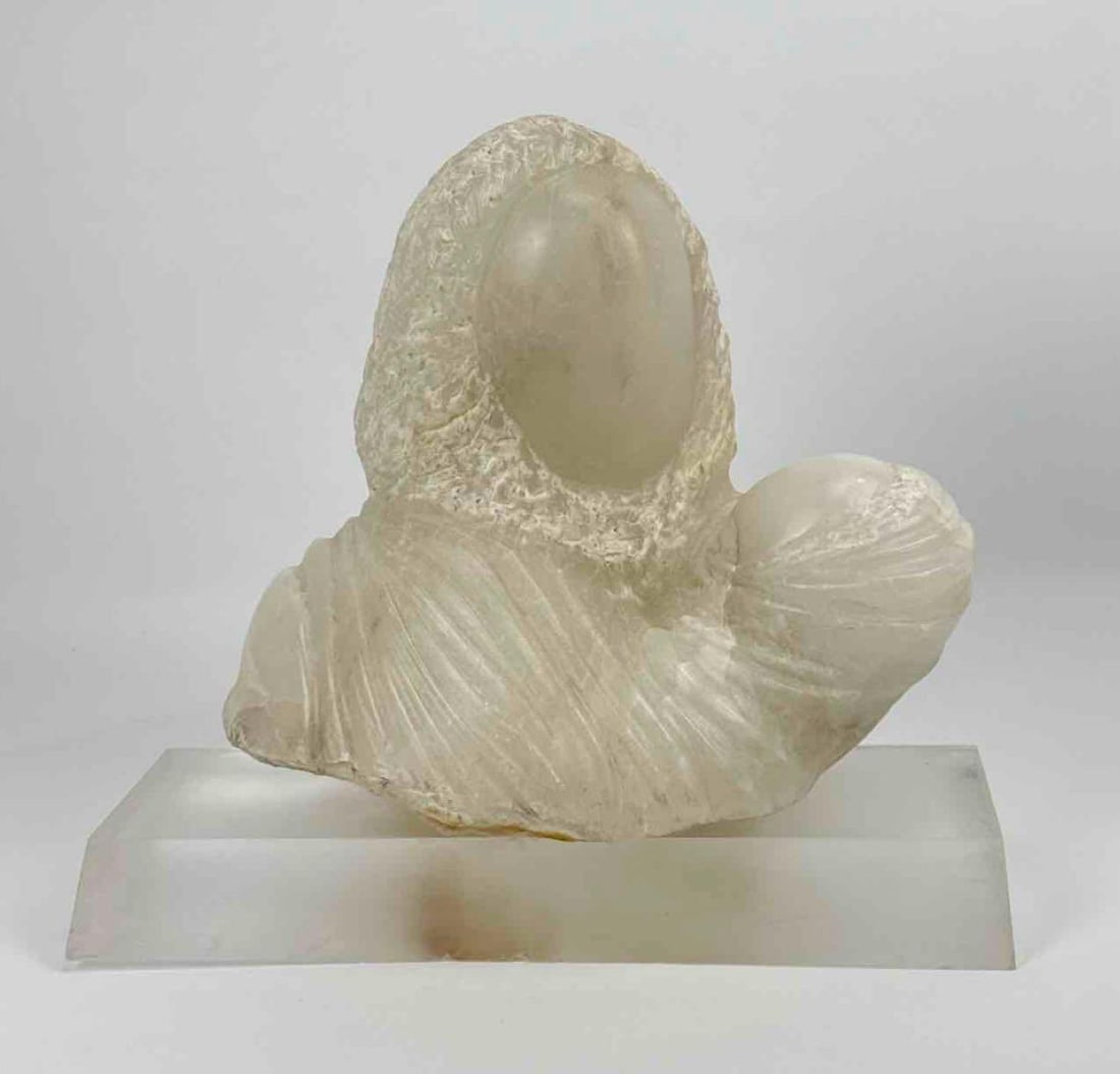 STYLIZED CARVED ALABASTER MADONNA AND CHILD BUST: Modernist stone sculpture depicting a stylized Mother and Child with textured and polished surfaces on a clear rectangular acrylic base. Approximate Dimensions: 13.25”h x15”w x 9”d A