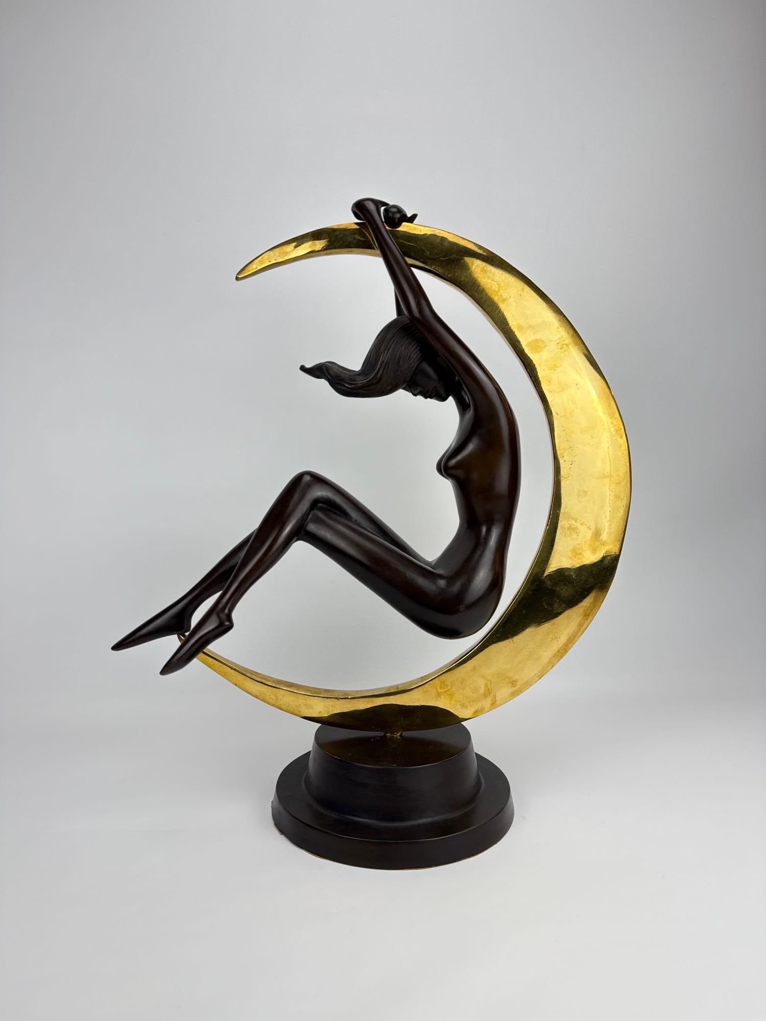 ROMAIN DE TIRTOFF ERTÉ-STYLE BRONZE NUDE FIGURE IN CRESCENT MOON SCULPTURE: Art Deco style dark patinated bronze female figure suspended within a polished gold-tone crescent moon on a tiered circular base. Approximate Dimensions: 23.5”h x 20.25”w x 9.5”dia a