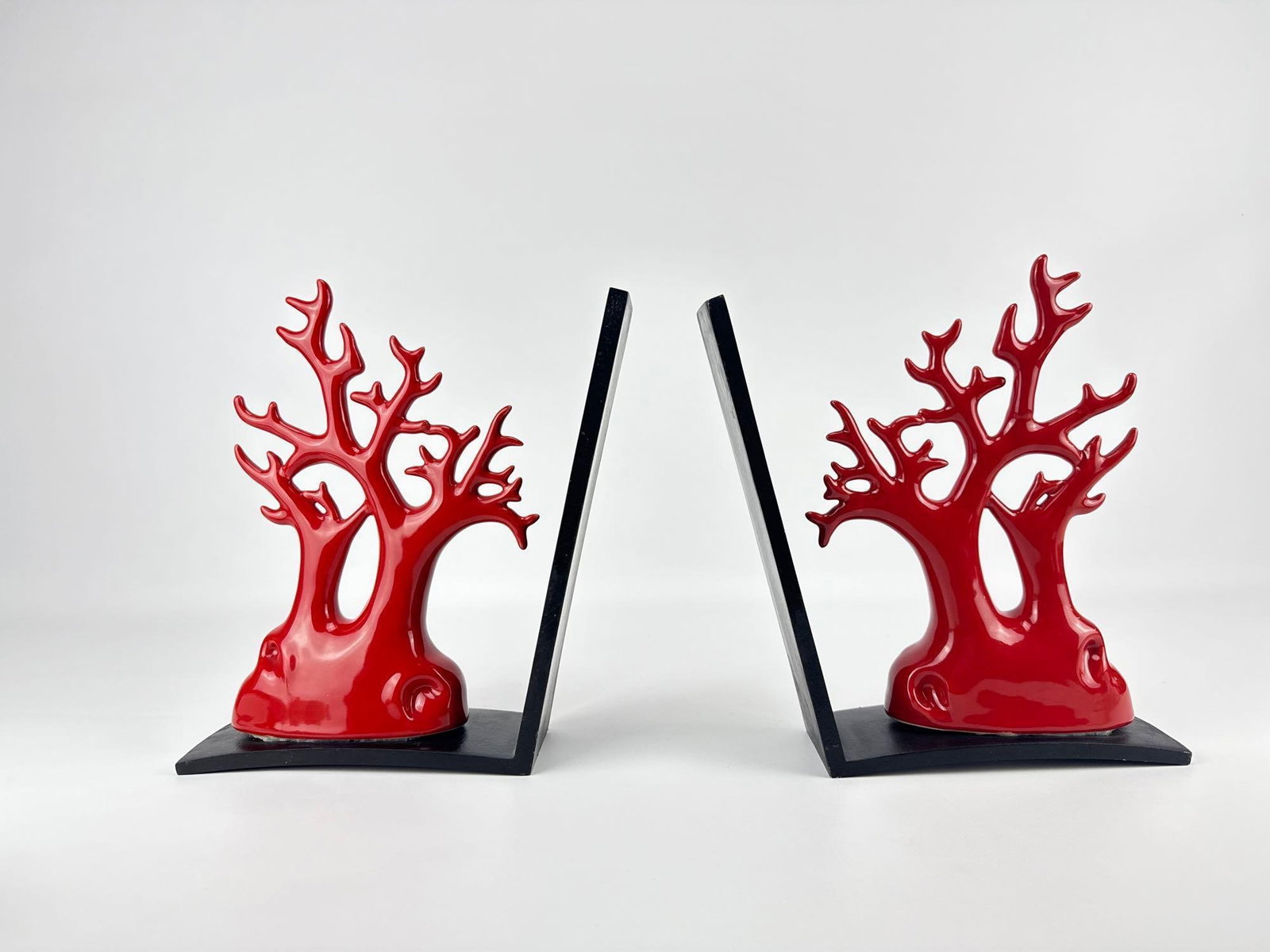 PAIR OF RED ENAMEL AND BLACK CORAL-FORM BOOKENDS: Decorative weighted book supports featuring branched sea coral in a vibrant red enamel finish, mounted on stepped rectangular black bases. Approximate Dimensions: 10.5”h x 10.25”w x 3&rdqu