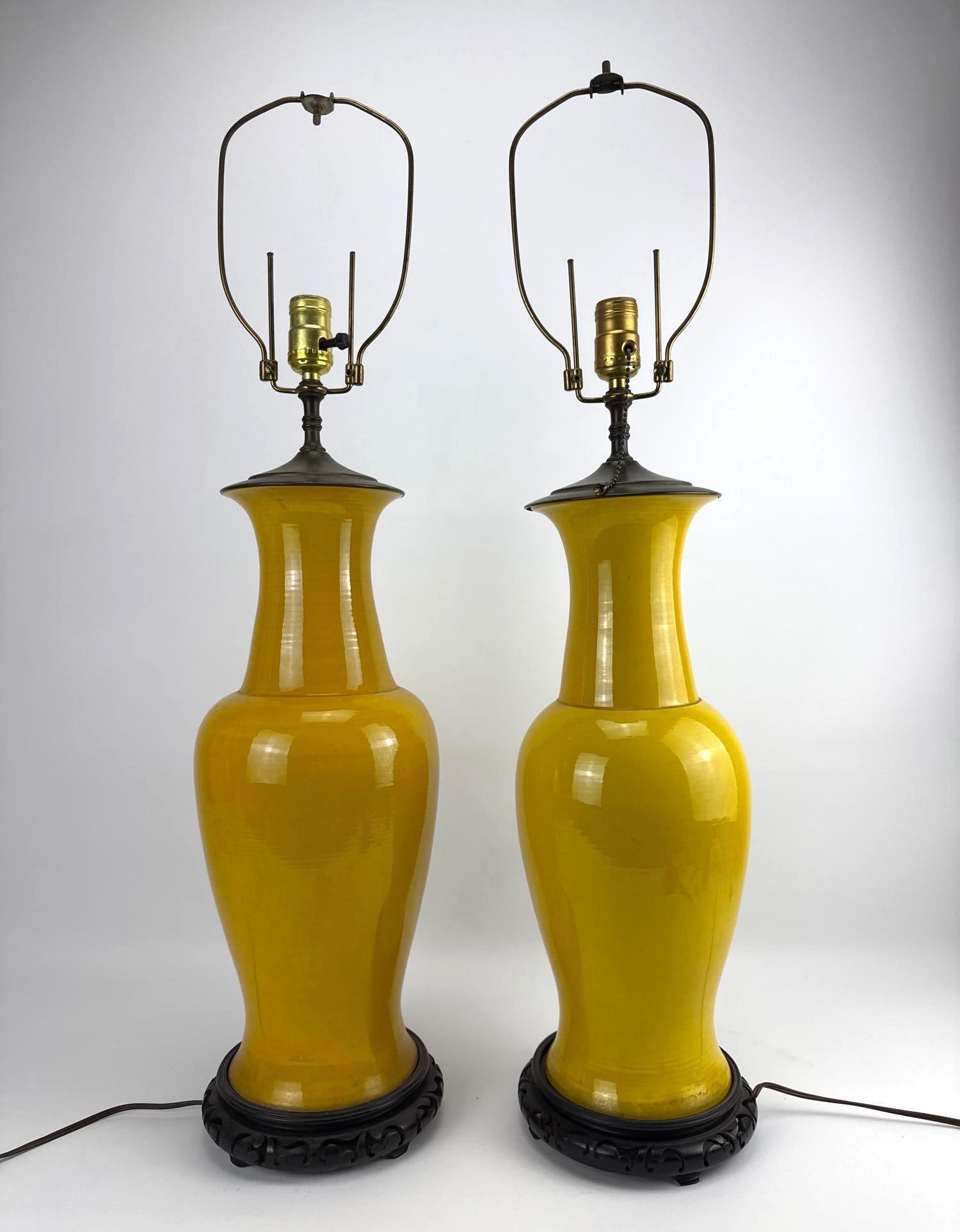 PAIR OF VINTAGE TYNDALE CHINOISERIE MUSTARD YELLOW CERAMIC LAMPS: Pair of tall mustard yellow glazed ceramic baluster-form lamps on carved dark wood bases. Approximate Dimensions: 26” AND 25.5" to top of socket Artist or Maker: Unknown Pro