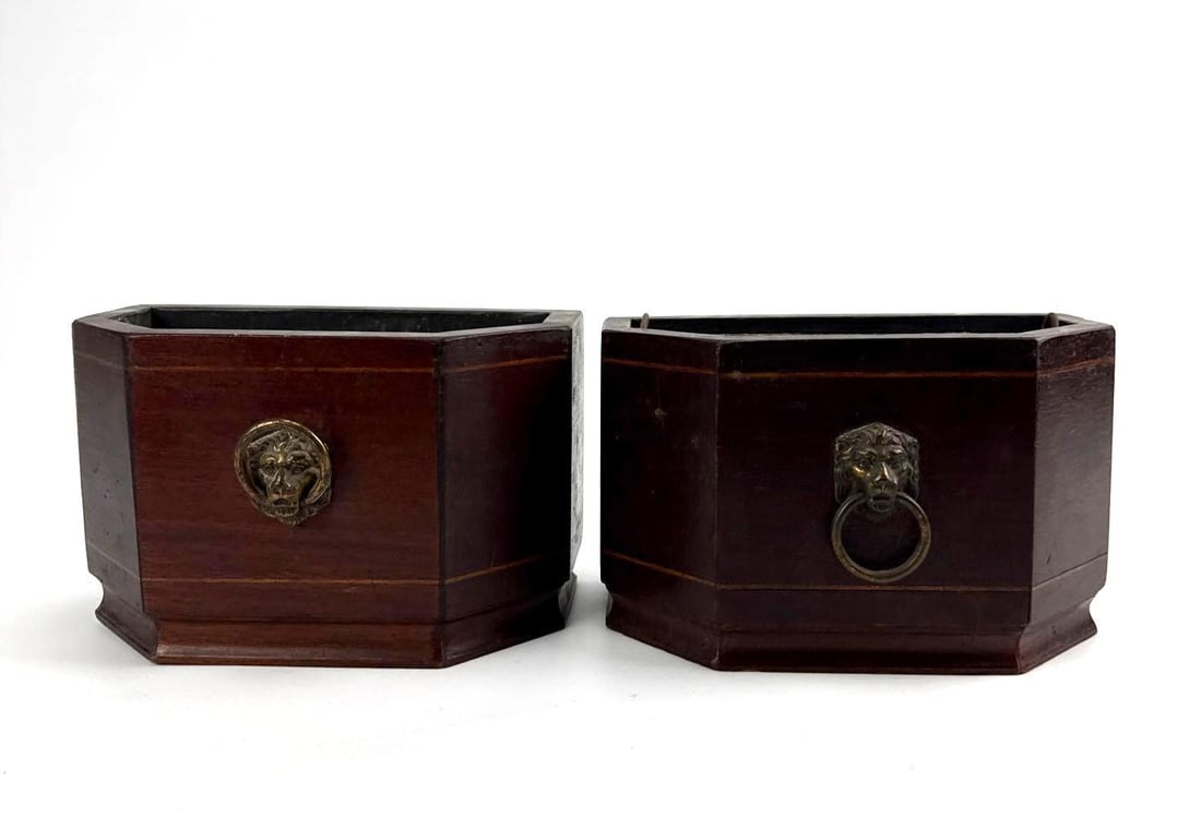 PAIR OF VINTAGE WOOD AND BRASS LION HEAD CACHEPOTS: Pair of dark stained octagonal wooden planters with inset brass lion-mask ring handles. Approximate Dimensions: 8” x 4”’x 5” h Artist or Maker: Unknown Provenance: F