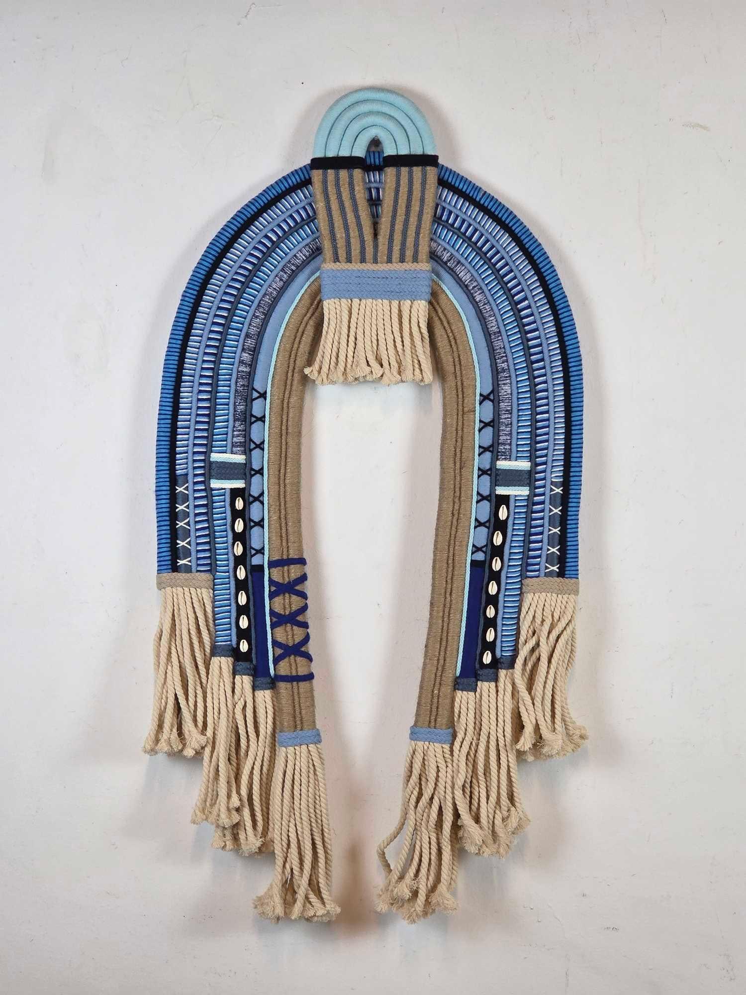 CONTEMPORARY AFRO-BRAZILIAN CANDOMBLÉ RITUAL ROPE SCULPTURE WITH COWRIE SHELLS: *Hand-woven fiber wall sculpture composed of blue and tan dyed rope with intricate cross-stitch binding, fringed ends, and natural cowrie shell embellishments representing Orixá religious traditions.