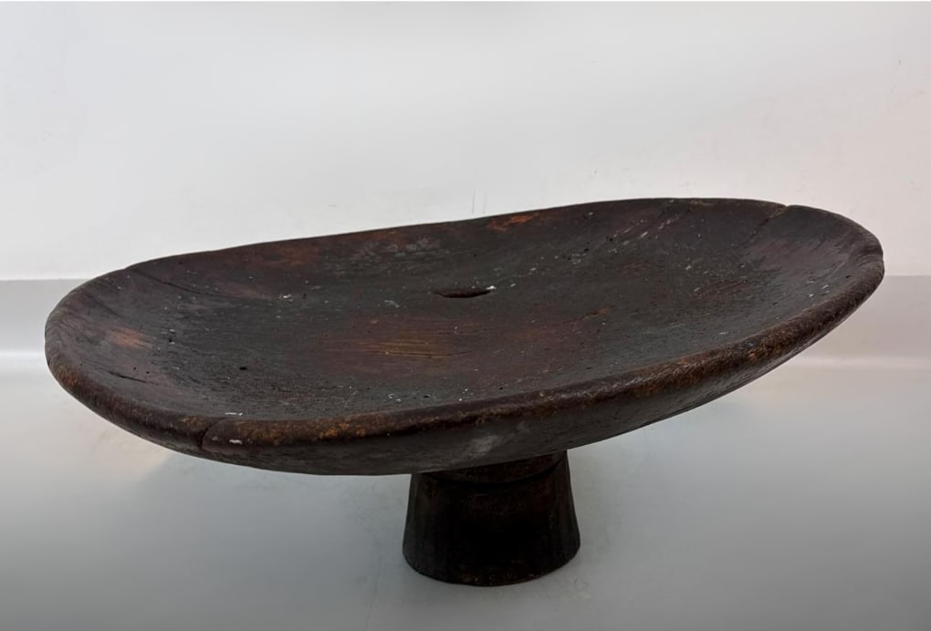 LARGE ANTIQUE MOROCCAN BERBER HAND-CARVED WOODEN TAZZABERBER TAZZA (2 OF 3): Large-scale rustic tribal offering bowl or low table carved from a single piece of hardwood with a pedestal base and iron ring handles. Approximate Dimensions: 11” h x27” dia Artist or Mak