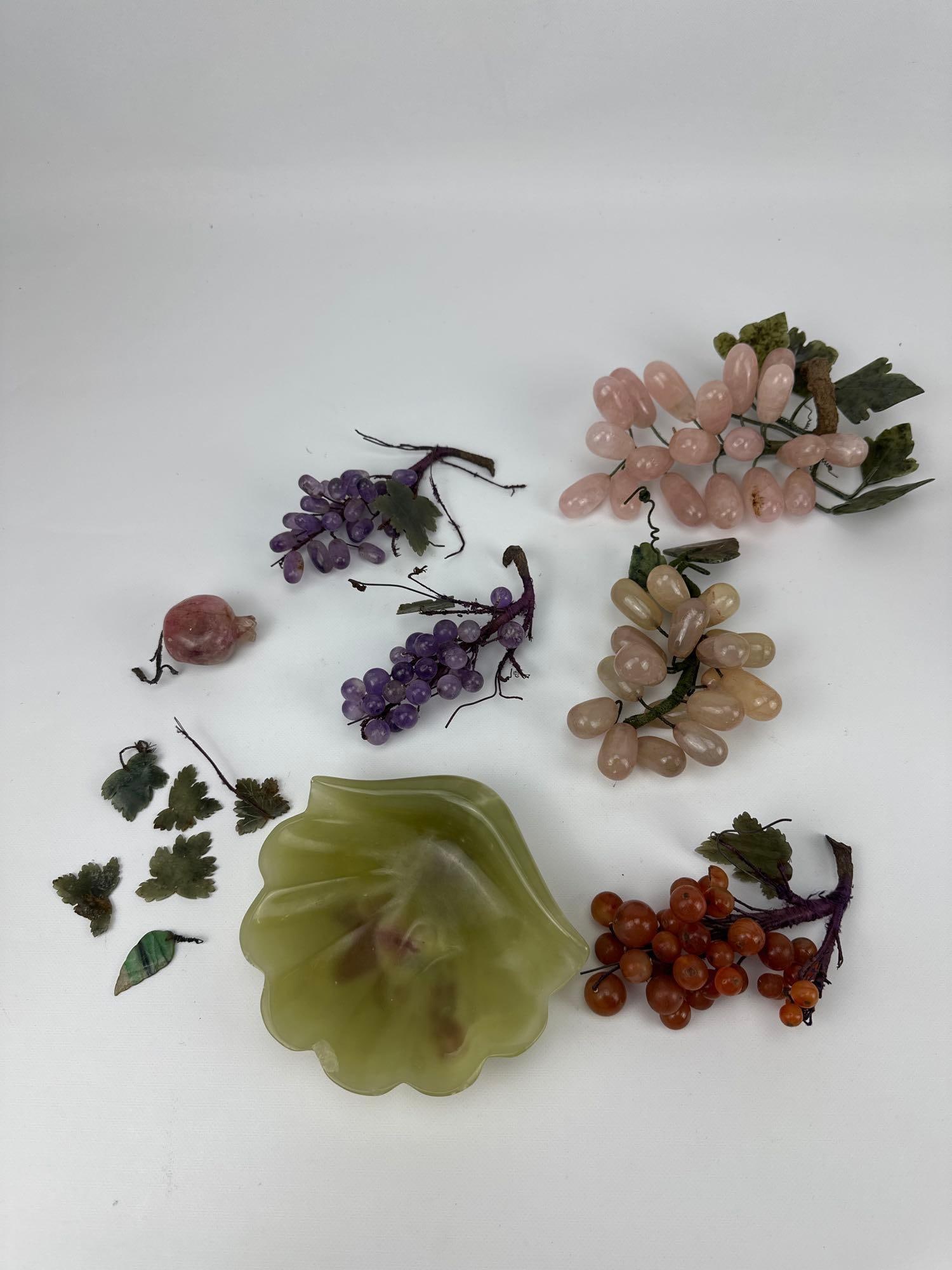 CHINESE SEMI-PRECIOUS HARDSTONE FRUIT GROUPS AND JADEITE BOWL: Collection of hand-carved quartz and jade fruit clusters alongside a carved celadon jadeite shell-form dish. Approximate Dimensions: Largest 8” long; dish: 6” x 5 Artist or Maker: Unknown