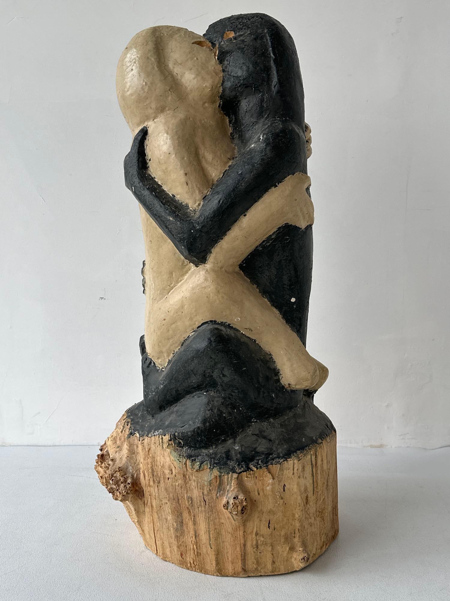 CONTEMPORARY FIGURATIVE CARVED WOOD SCULPTURE OF EMBRACING COUPLE: *Large-scale hand-carved wooden sculpture depicting two intertwined figures in an embrace, featuring a contrasting painted black and natural cream finish, integrated into a raw timber trunk base. Appr