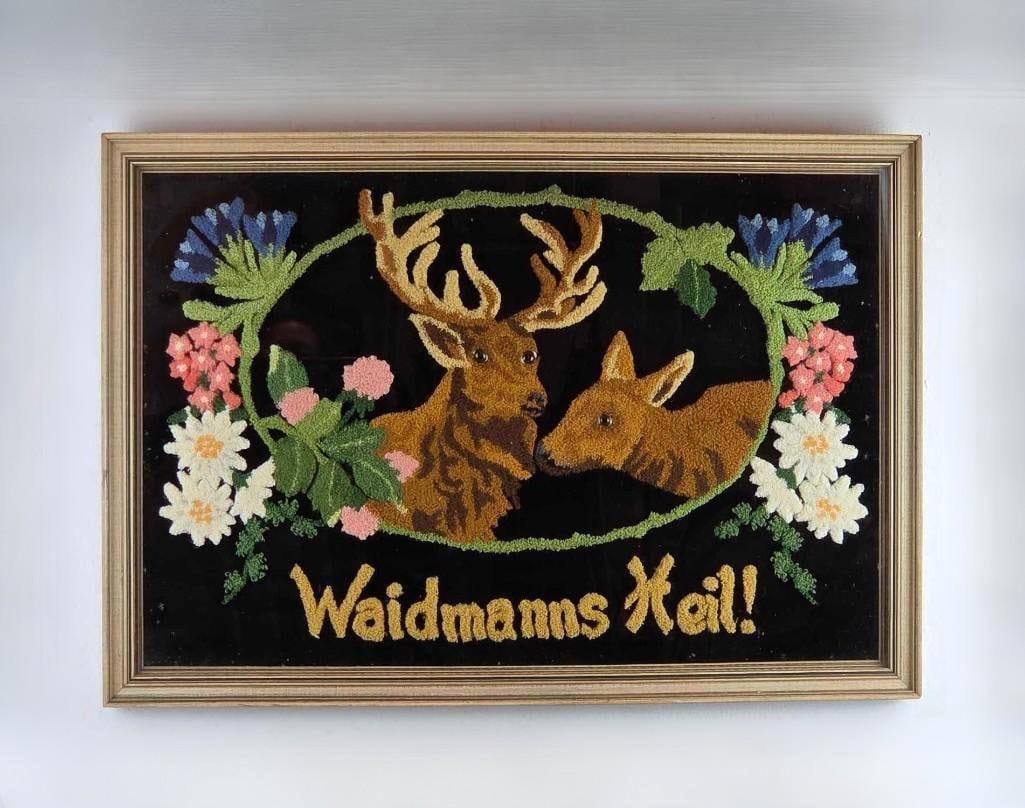 WAIDMANNS HEIL “GOOD HUNTING?? WAIDMANNSHEIL FRAMED DEER PUNCH NEEDLE: Vintage German punch-needle textile art on black fabric depicting a stag and a doe with a floral border and the hunter’s greeting "Waidmanns Heil!" Overall Approximate Dimensions: 18.25"