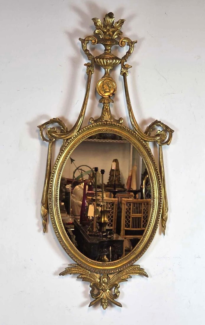 FINE ITALIAN NEOCLASSICAL CARVED GILT WOOD MIRROR WITH URN AND SWAG MOTIF: An elegant 18th-century style Italian neoclassical mirror featuring a central oval plate set within a highly ornate hand-carved giltwood frame. Approximate Dimensions: 48" X 24" Artist or Make