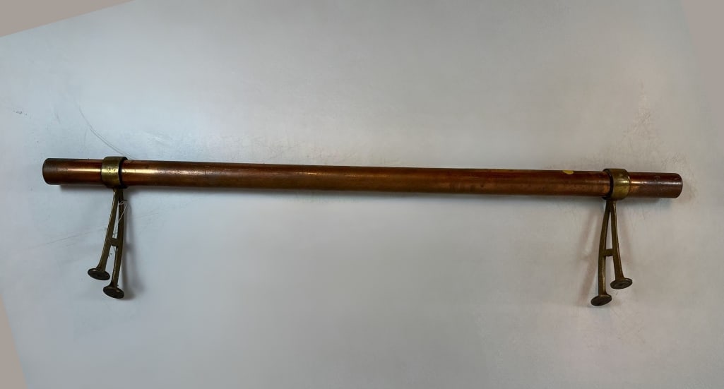 VINTAGE AMERICAN COPPER AND BRASS BAR FOOT RAIL: 46-inch heavy copper tubing with two adjustable brass combination floor-mount brackets Approximate Dimensions: 10” x 46” long x 2” dia bar Artist or Maker: Unknown P