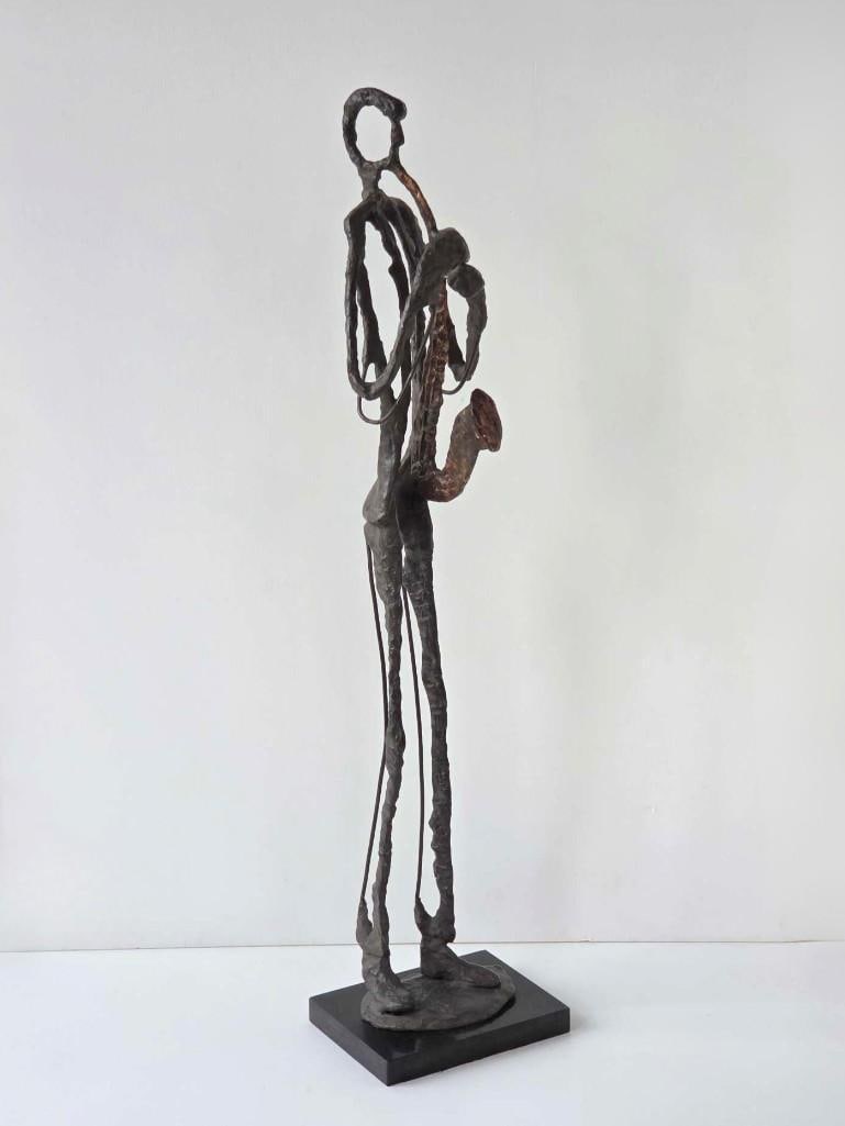 LARGE MODERNIST BRUTALIST SAXOPHONE PLAYER SCULPTURE: Elongated hand-wrought dark patinated metal figure of a jazz musician playing the saxophone on a rectangular black base. Approximate Dimensions: 38.5"h x 8.25"w x 7"d Artist or Maker: Unkn