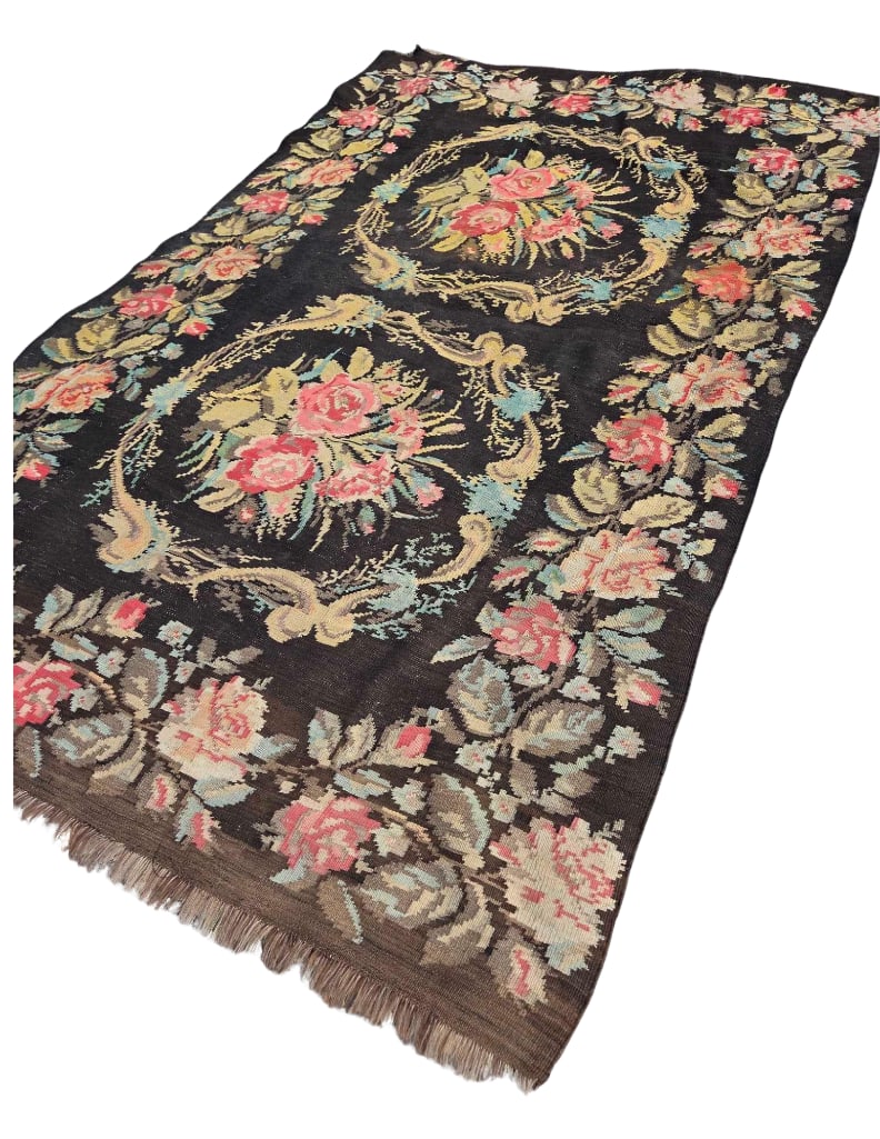 BESSARABIAN FLORAL KILIM RUG C. 1920's: A handwoven flat-weave wool carpet featuring a double medallion design with lush rose bouquets on a chocolate brown ground. Approximate Dimensions:Â 9'1" x 5'9" Artist or Mak
