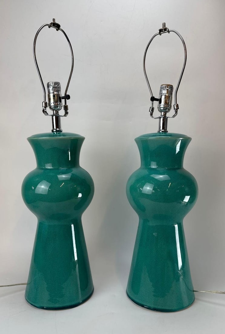 PAIR OF VINTAGE MID-CENTURY TEAL GREEN GLAZED CERAMIC LAMPS: Pair of mid-century modern hourglass-form ceramic table lamps featuring a vibrant, glossy teal green crackle-glazed finish on flaring conical bodies with polished chrome hardware necks. Approximate Di