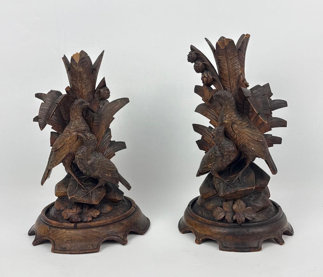 PAIR OF ANTIQUE HAND CARVED BLACK FOREST CANDLE HOLDERS: A fine pair of 19th-century German or Swiss Black Forest antique candlesticks, exquisitely hand-carved from dense, rich walnut wood. Each pillar depicts a highly detailed rustic wildlife scene featuri