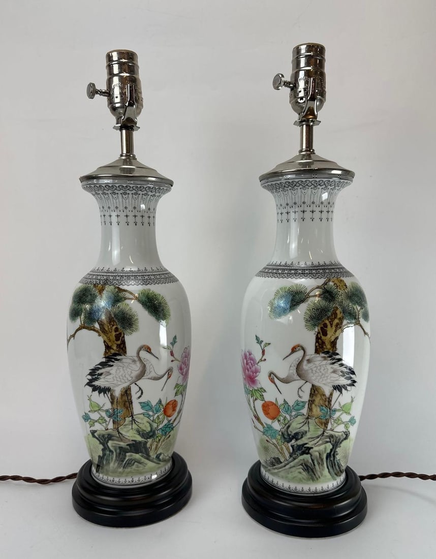 PAIR OF VINTAGE FAMILLE ROSE CRANE LAMPS: Pair of vintage traditional Chinese porcelain baluster table lamps featuring hand-painted Famille Rose enamels depicting red-crowned cranes beneath a pine tree with blooming peonies and peaches, mount