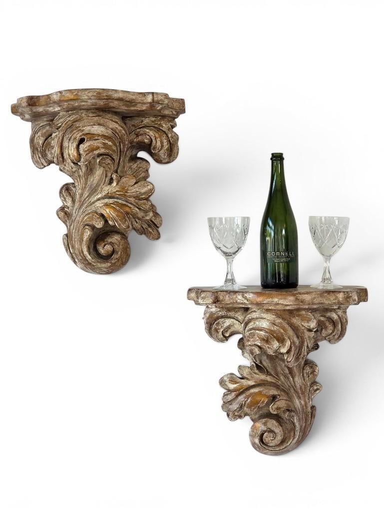 PAIR OF VINTAGE ITALIAN STYLE FLORENTINE CARVED GILT COMPOSITE WALL BRACKET SHELVES: A pair of baroque style wall-mounted bracket shelves, intricately detailed with scrolling acanthus leaves finished in a heavily distressed antique gold and cream lacquer patina. Approximate