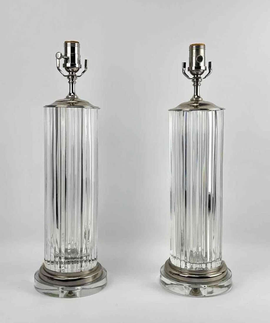 PAIR OF ART DECO REVIVAL FLUTED GLASS COLUMN LAMPS: *A pair of sophisticated table lamps featuring tall, heavy, cylindrical clear glass bodies with deep vertical fluting, mounted on stepped circular glass and polished nickel or chrome bases.