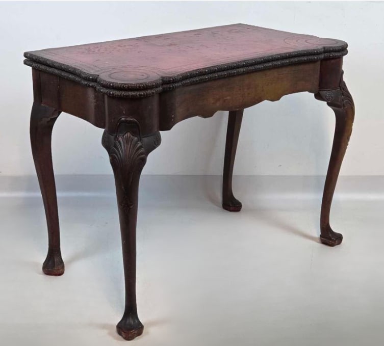 VINTAGE LEATHER TOP FOLDOVER GAME TABLE: *Expandable mahogany-finish fold-over card table with tool-embossed red leather playing surface, shell-carved cabriole legs, and ball-and-claw feet. Approximate Dimensions: 30.25"h x 39"w x 21