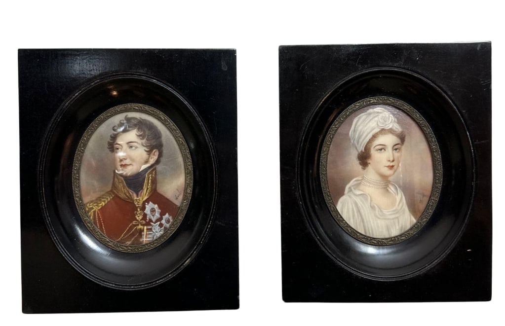 PAIR OF ANTIQUE MINIATURE PORTRAITS IN CONVEX GLASS EBONIZED FRAMES: *Pair of 19th-century oval hand-painted miniature portraits on ivory depicting a Regency-era gentleman in military attire and a lady in a white turban under convex glass within square ebonized wood fr