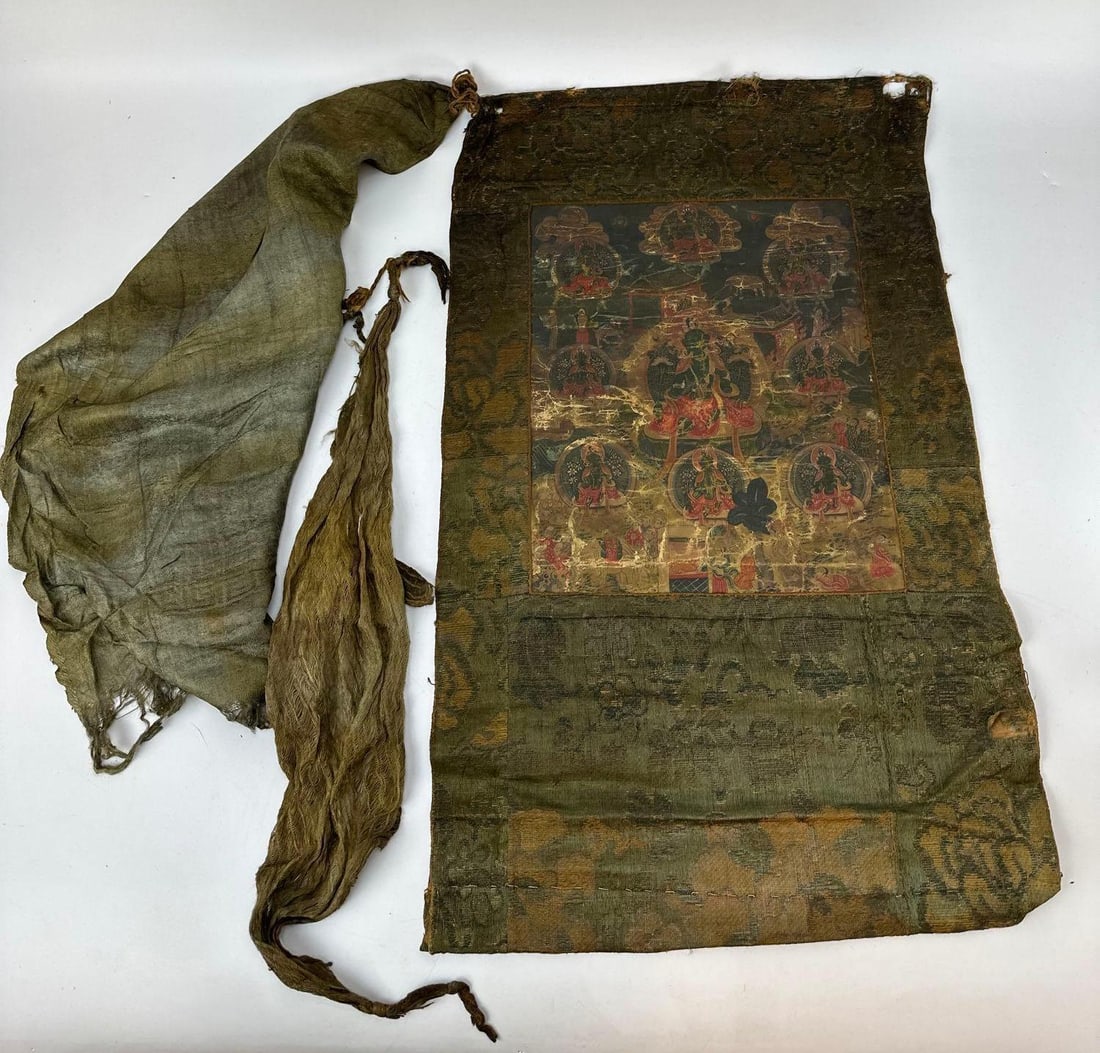 ANTIQUE TIBETAN THANGKA GREEN TARA BUDDHIST DEVOTIONAL SCROLL PAINTING: An antique Himalayan devotional thangka painting on fabric measuring 22” x 14” depicting a central green tara deity surrounded by smaller manifestations within a traditional, heavily