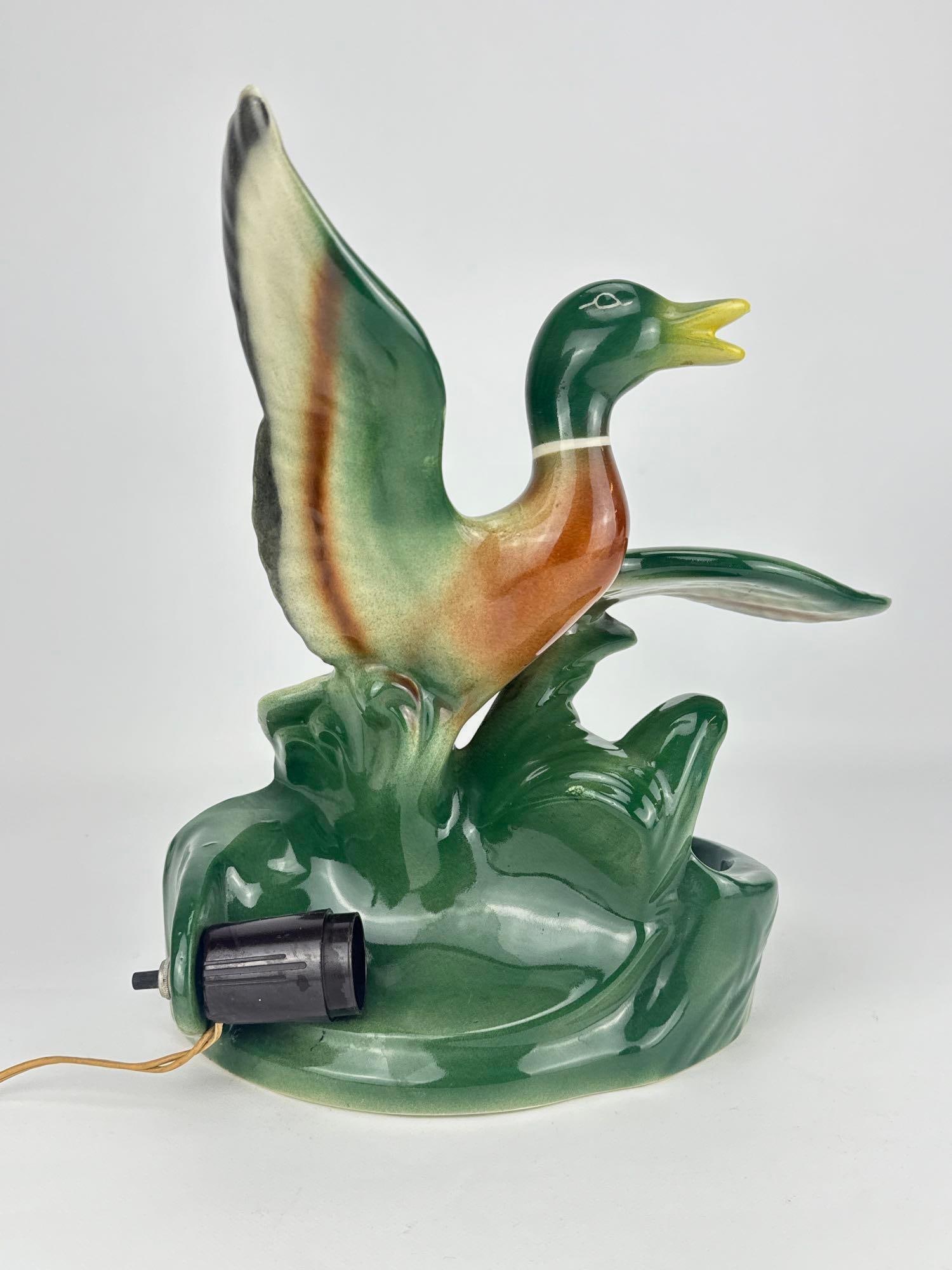 VINTAGE MALLARD DUCK CERAMIC TV LAMP IN THE MANNER OF KRON OR LANE & CO: A vintage mid-century glazed ceramic television lamp sculpted as a mallard duck taking flight from a green marsh base, complete with an attached electrical cord and light socket. Approximate Dimension