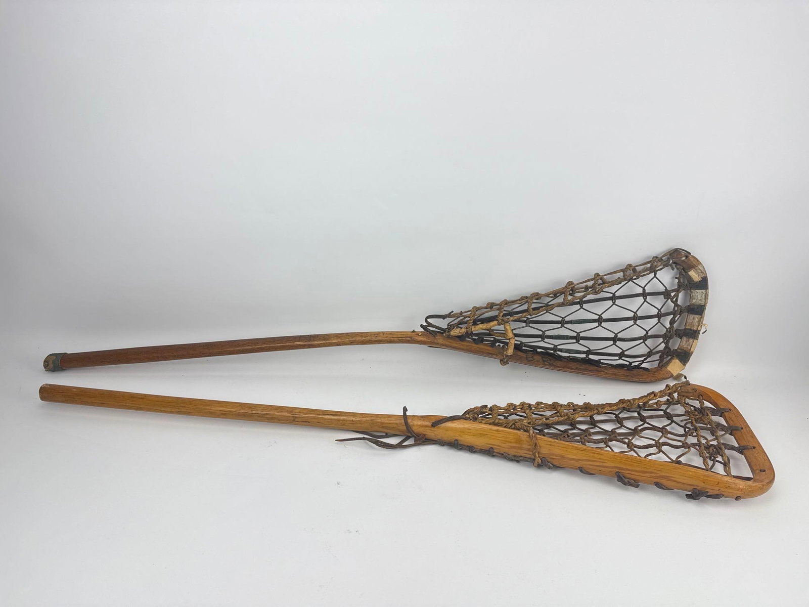 ANTIQUE WOODEN LACROSSE STICKS NATIVE AMERICAN ATTR.: Pair of early 20th-century traditional steam-bent ash wooden lacrosse sticks. Approximate Dimensions: 43” L x 9”W Artist or Maker: Unknown Provenance: From a New
