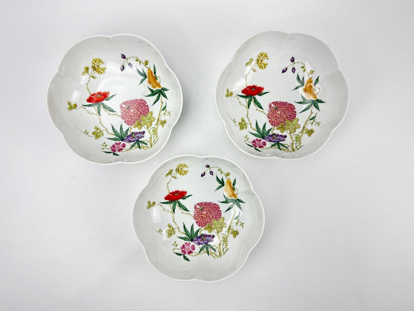 TRIO OF LARGE RAYNAUD & CO LIMOGES CERALENE FLORAL PORCELAIN BOWLS: Three matching large French fine china serving bowls adorned with a vibrant hand-painted multi-colored botanical floral pattern and scalloped lobed borders. Approximate Dimensions: 3.5"h x 9.5"