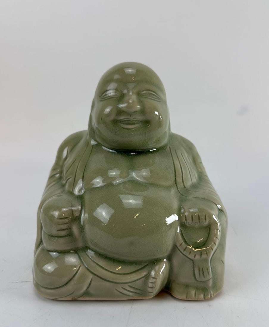 CHINESE CELADON CRACKLE GLAZE PORCELAIN HOTEI / LAUGHING BUDDHA FIGURINE: 20th-century Chinese porcelain seated figure of Hotei (the Laughing Buddha) holding a prayer sack covered in a thick glossy sage-green celadon glaze and under-glaze crackle lines. Approximate Dimensio