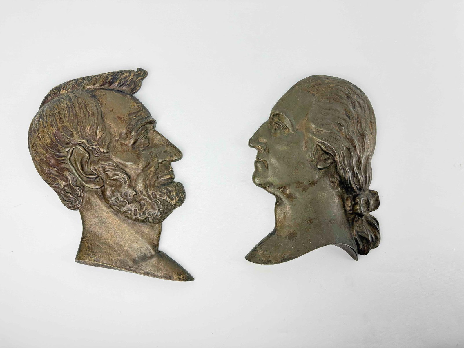 PAIR OF ANTIQUE CAST IRON GEORGE WASHINGTON AND ABRAHAM LINCOLN PROFILE RELIEF PLAQUES: Pair of late 19th to early 20th-century American highly detailed portrait busts of Presidents George Washington and Abraham Lincoln hollow-back cast metal wall plaques. Approximate Dimensions: Lincoln