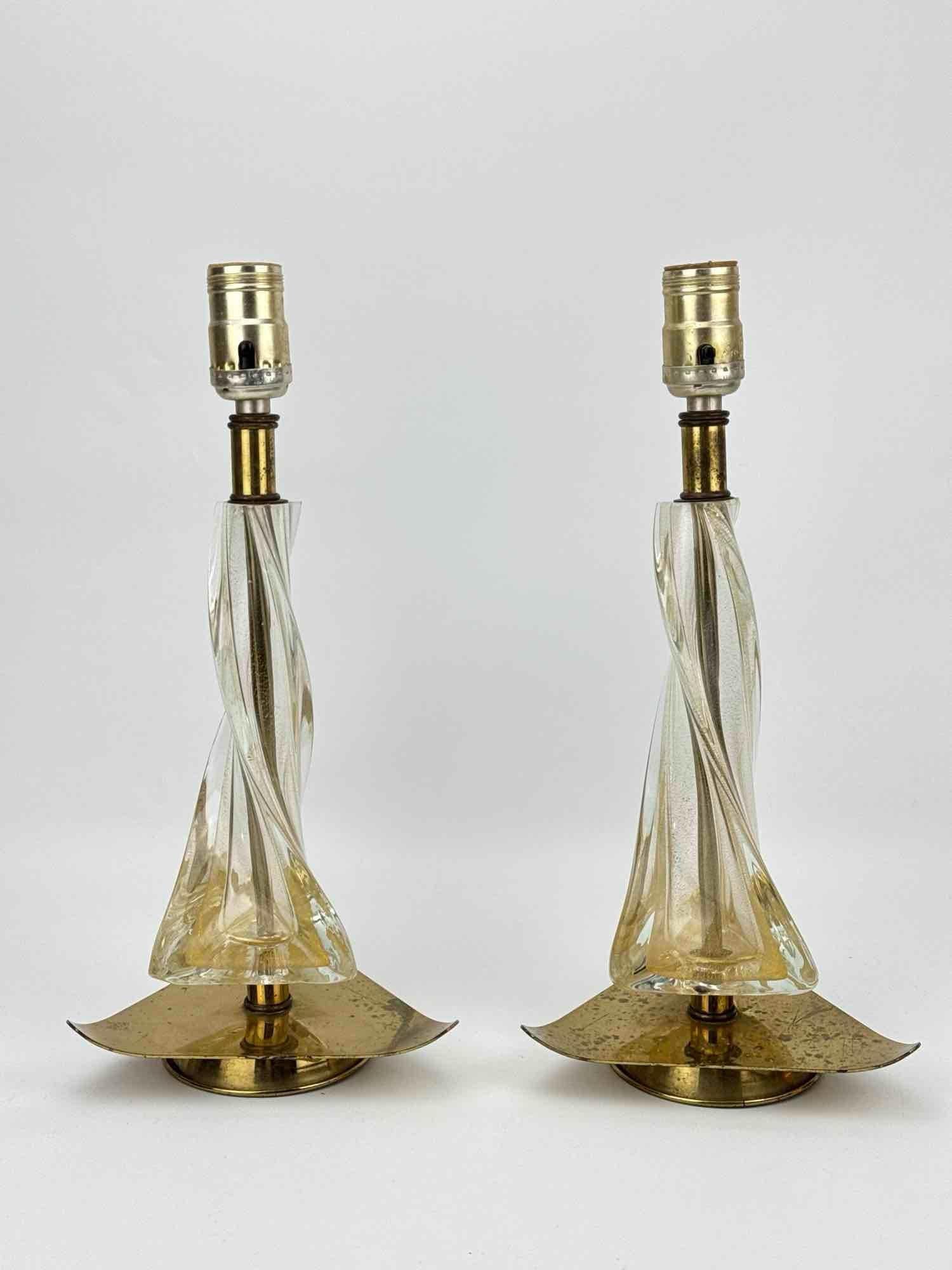PAIR OF MURANO STYLE MID CENTURY TWISTED ART GLASS LAMPS: Pair of 19th-century inspired mid-century modern table lamps with gold fleck aventurine twisted clear art glass bodies on swooping triangular brass-tone metal bases. Approximate Dimensions: 14”h
