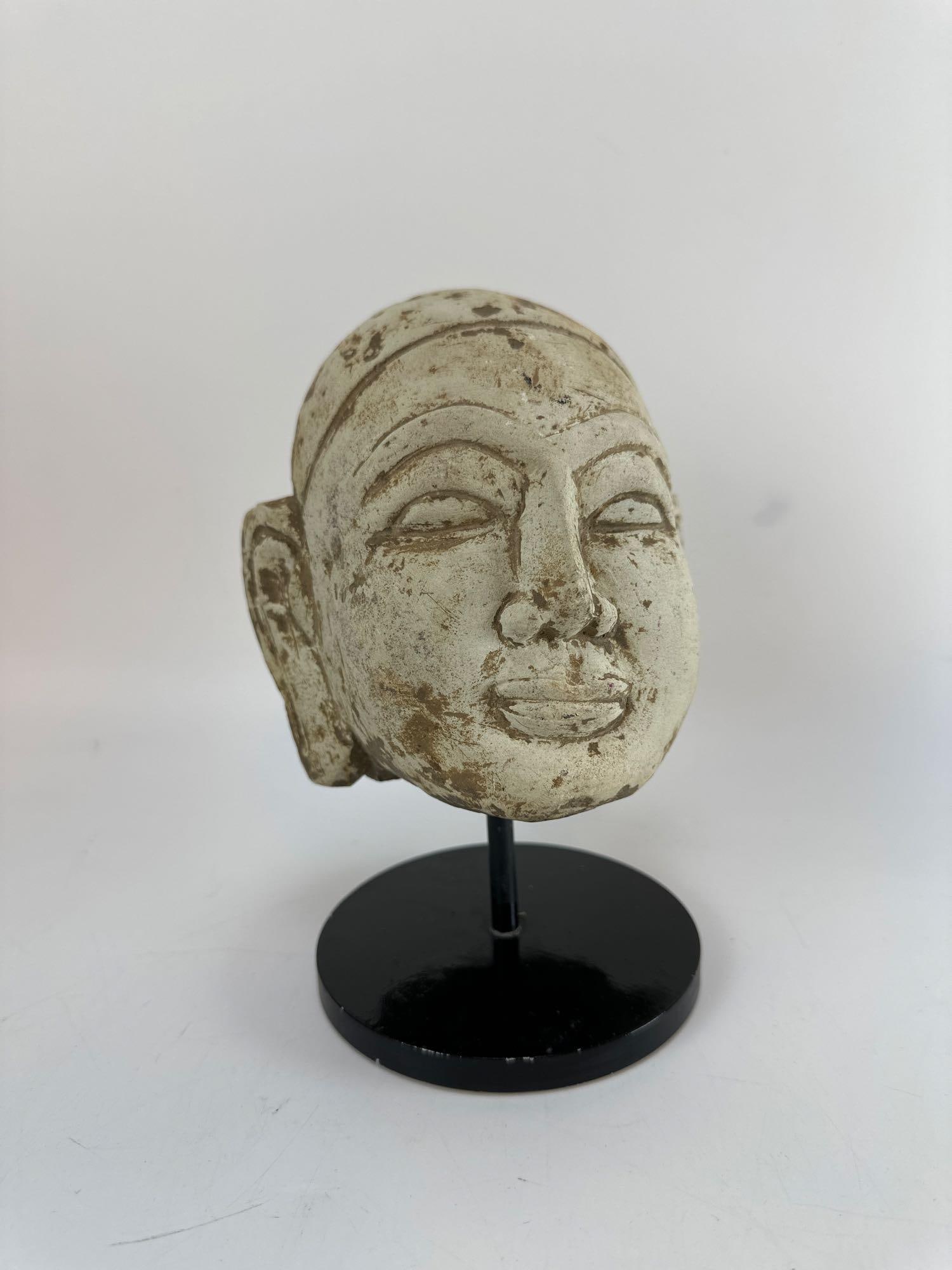 ANTIQUE SOUTHEAST ASIAN CARVED STONE BUDDHA HEAD ON MOUNTED STAND: Decorative carved stone head of the Buddha styled after classical Southeast Asian (possibly Khmer or Thai) temple fragments. Approximate Dimensions: 6”x6”x 8.5” tall Artist or Maker: