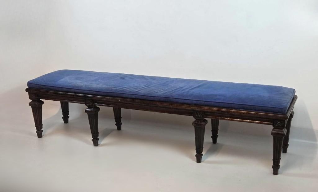 ANTIQUE LOUIS XVI STYLE CARVED WALNUT UPHOLSTERED BENCH (SIX FEET, NINE INCHES LONG): *A long neoclassical window bench with eight fluted legs and a removable cushion with blue fabric upholstery. Approximate Dimensions: 20"H x 81"W x 20"D Artist or Maker: Unknown Provenance