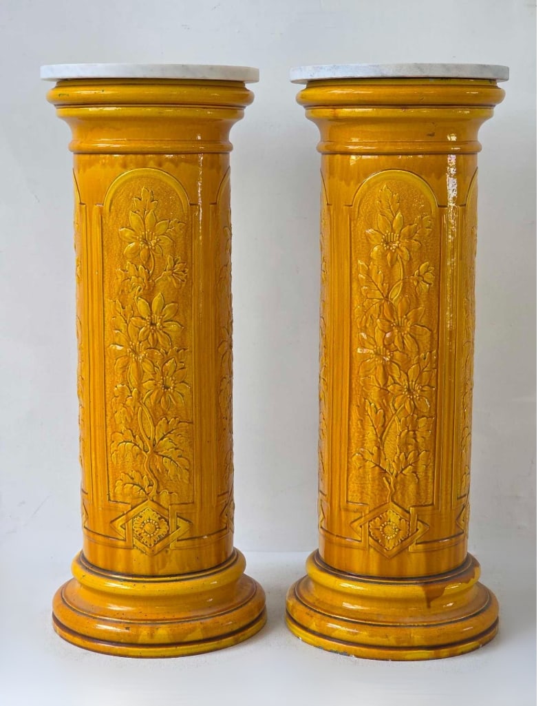 PAIR OF ANTIQUE VICTORIAN BURMANTOFTS FAIENCE OCHRE YELLOW GLAZED CERAMIC COLUMN PEDESTALS: A pair of late 19th-century English Arts and Crafts style faience majolica pottery cylindrical columns decorated with molded botanical foliate scrollwork in relief under a glossy yellow-ochre glaze wi