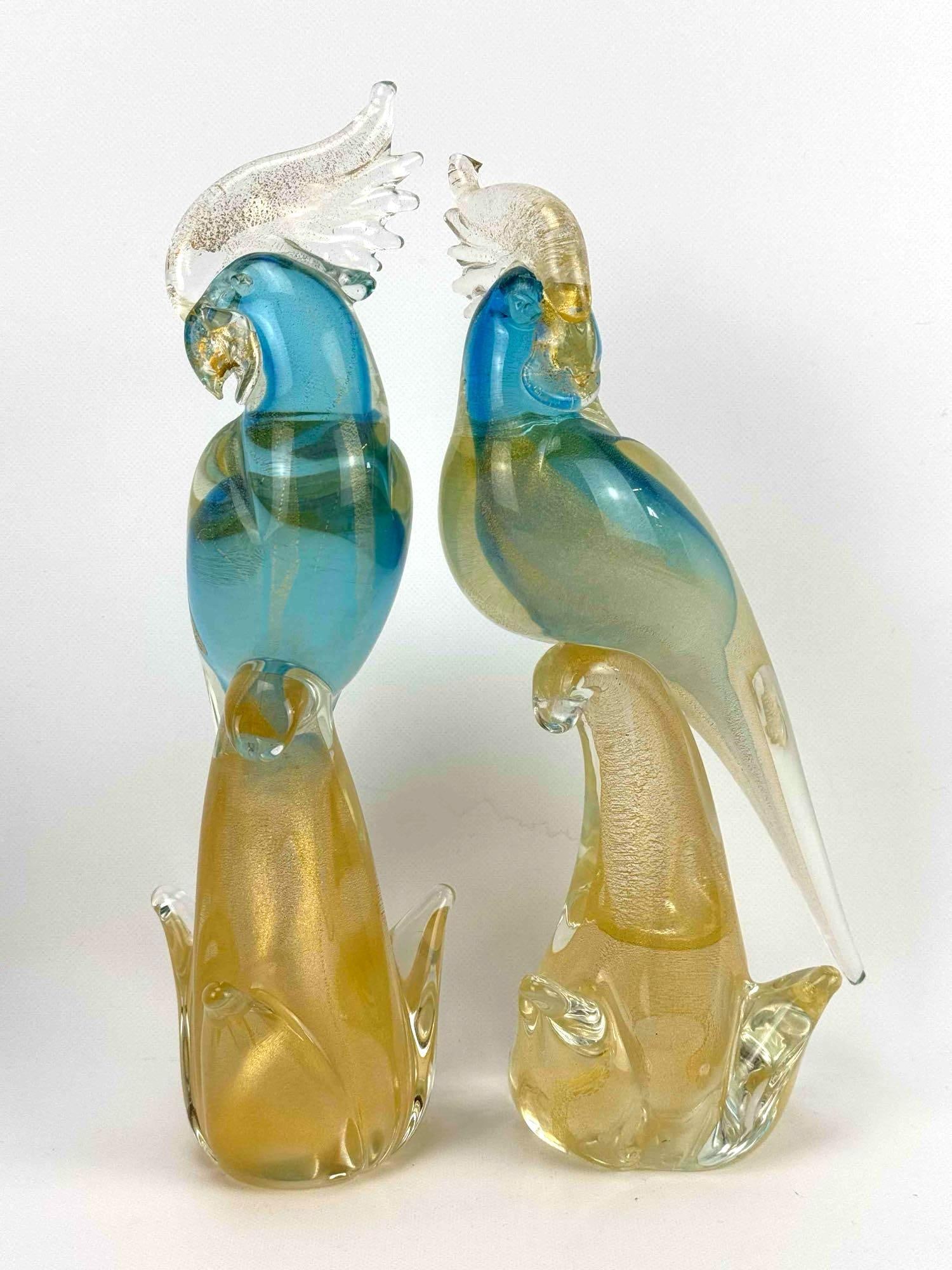 PAIR OF MURANO ITALIAN GOLD AVVENTURINA AND BLUE GLASS COCKATIELS FIGURINES: Two mid-century hand-blown Italian art glass tropical cockatoo sculptures with shimmering gold flecked crests and bases supporting translucent blue and green bird bodies. Tallest Approximate Dimension