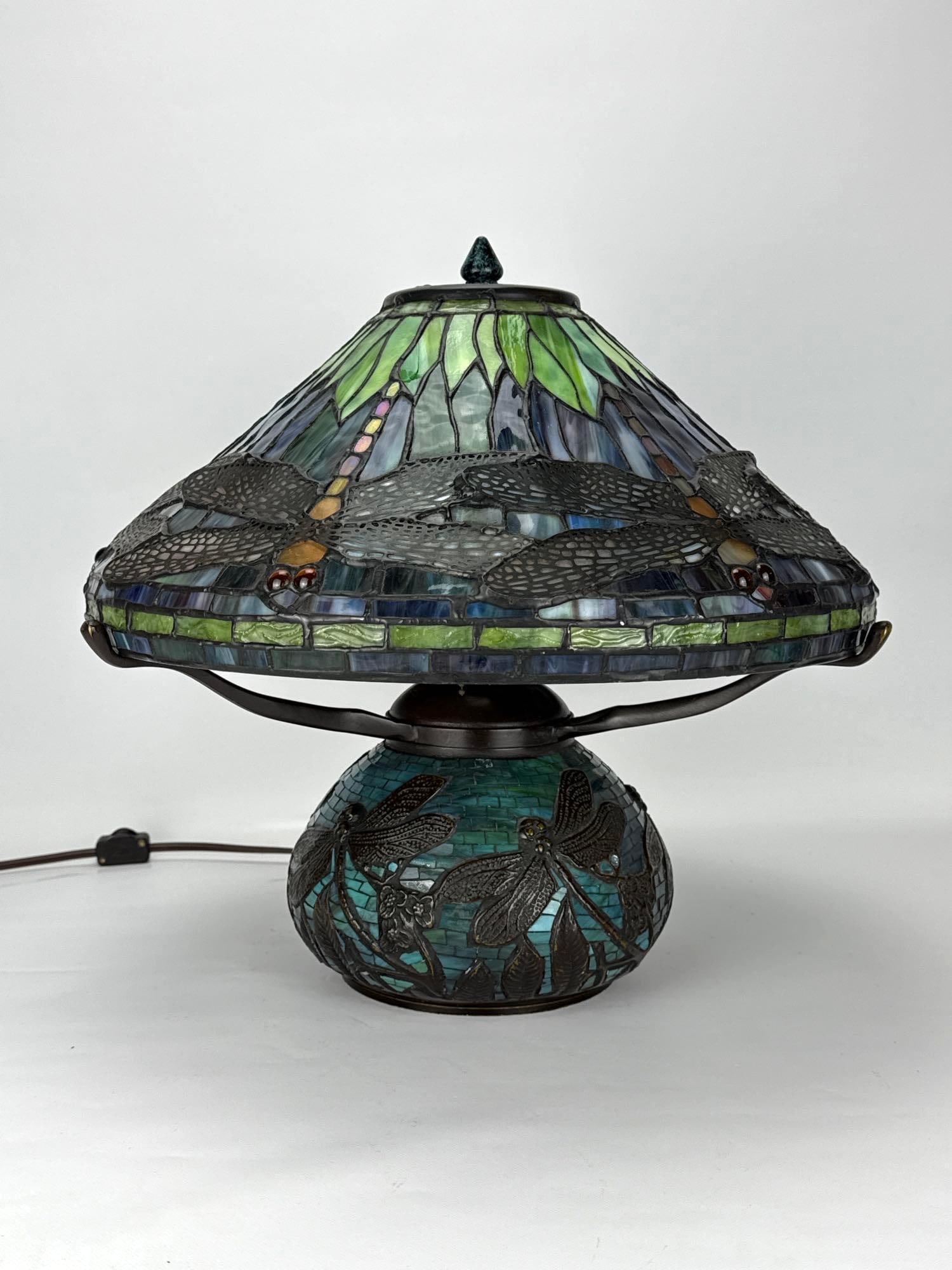 DALE TIFFANY DRAGONFLY LEADED STAINED GLASS AND MOSAIC BASE TABLE LAMP: A stunning, art nouveau style table lamp containing a conical leaded glass shade with a repeating dragonfly motif in shades of green, blue, and amber, resting on a matching lighted mosaic glass and pa