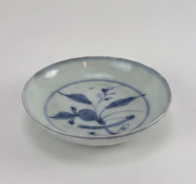 CHINESE BLUE AND WHITE PORCELAIN DISH WITH QIANLONG STYLE SEAL MARK: Small Chinese underglaze blue and white porcelain saucer dish painted with a stylized floral and fruit branch motif. Approximate Dimensions: 4” Dia. Artist or Maker: Chinese kiln; the underglaze