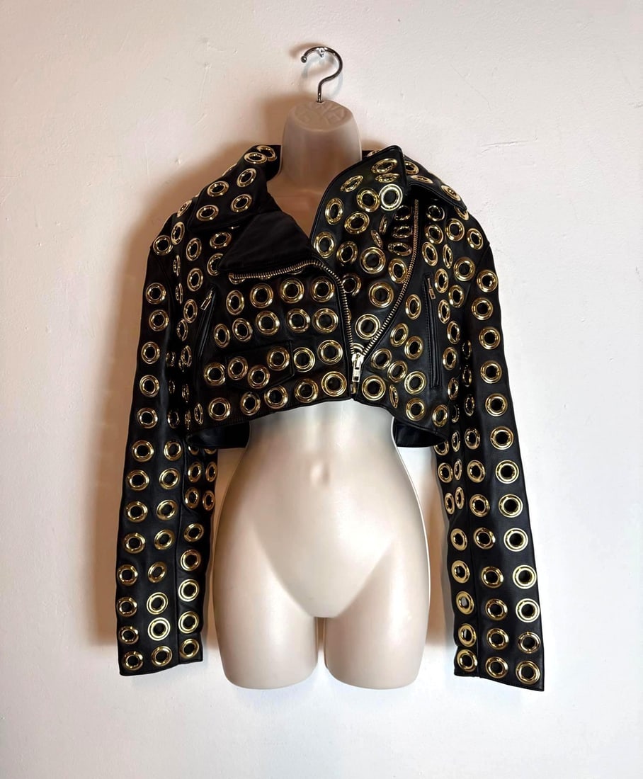MOSCHINO COUTURE JEREMY SCOTT BLACK LEATHER GOLD GROMMET CROPPED BIKER JACKET: A cropped black leather motorcycle jacket densely embellished with polished gold-tone metal grommets and asymmetrical zip hardware. Original Retail: $8,995.00 Size: I-40 D-34 F-36 GB-8 USA-6 <
