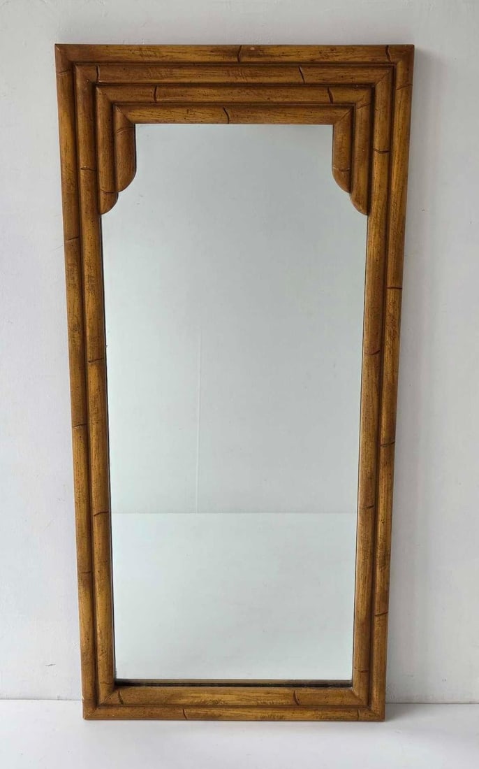 VINTAGE HOLLYWOOD REGENCY STYLE FAUX BAMBOO RECTANGULAR WALL MIRROR: Vintage mid-century Hollywood Regency style rectangular wall mirror with a warm honey-toned turned faux bamboo frame accented by inset stepped corners Approximate Dimensions: 41.25"h x 19.25"w