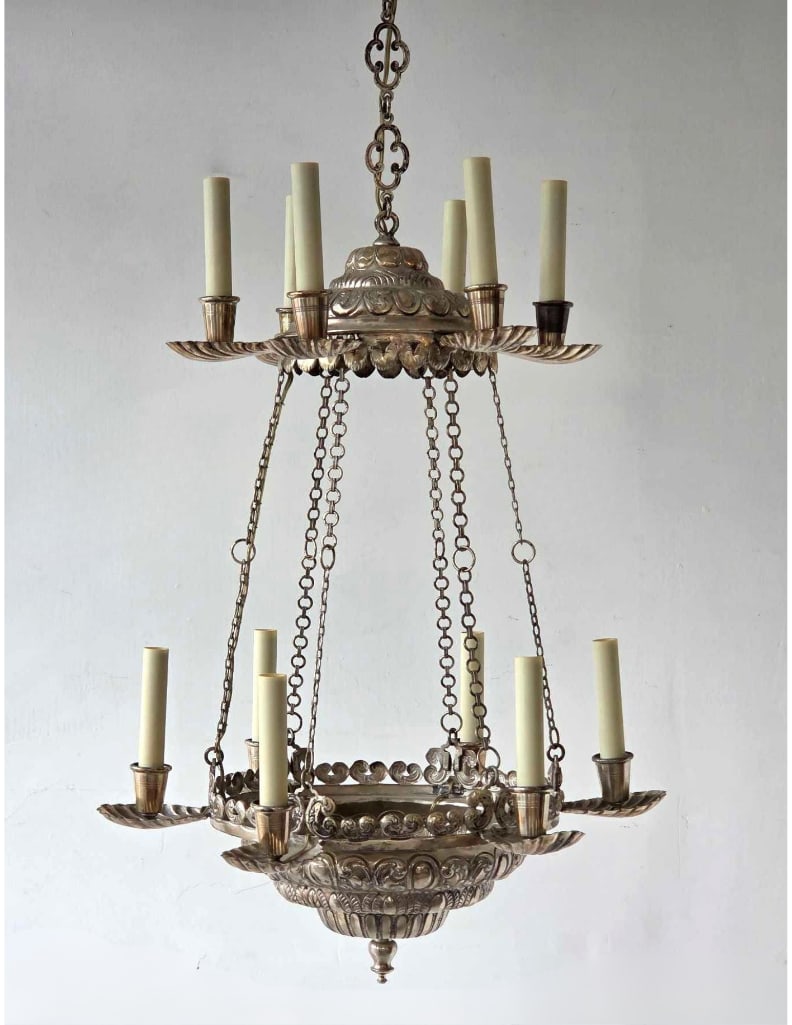 ANTIQUE SPANISH COLONIAL STYLE TWELVE ARM TWO TIER SILVERED COPPER CHANDELIER: Antique Spanish Colonial revival style two-tier twelve-arm hanging light fixture in silvered copper detailed with ornate repousse scrollwork and prominent scalloped sea shell form bobeches Approximate