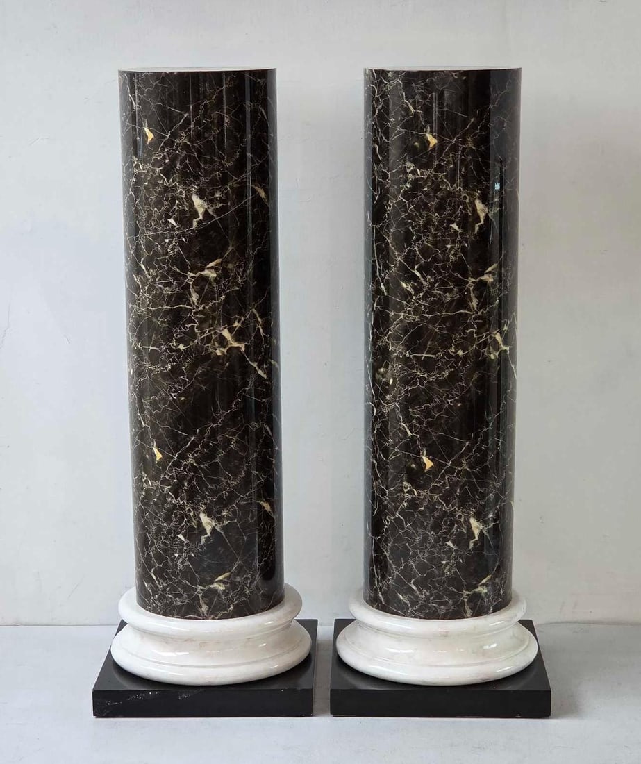PAIR OF LARGE POSTMODERN FAUX MARBLE ARCHITECTURAL COLUMNS: Pair of architectural pedestals designed as classical columns with highly polished faux black marquina marble shafts highlighted by golden veins, resting on molded faux white marble plinths and dark s