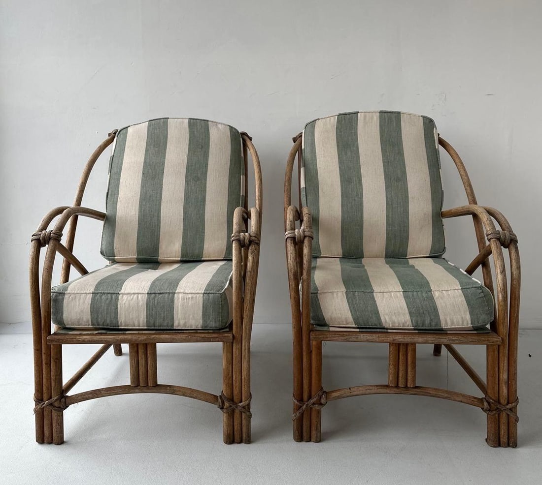 PAIR OF VINTAGE BOHEMIAN RATTAN AND BAMBOO LOUNGE CHAIRS: Matched set of two mid-century style bentwood rattan armchairs featuring triple-pole construction, flared armrests, and decorative cane bindings, fitted with striped sage green and cream reversible cu