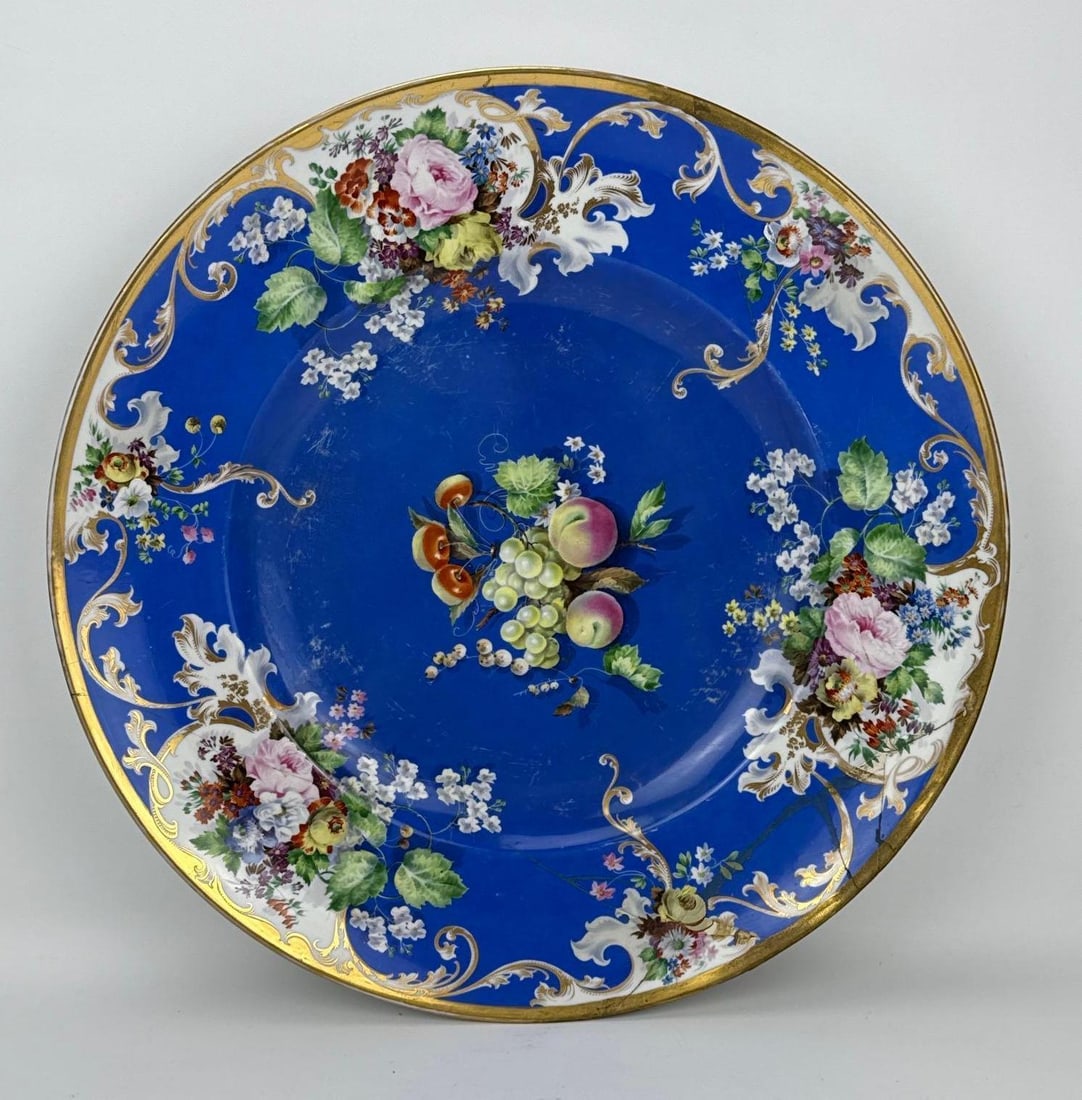NINETEENTH CENTURY SÈVRES STYLE COBALT BLUE HAND-PAINTED PORCELAIN CHARGER WITH STAPLE REPAIRS: Large nineteenth century Sèvres style hand-painted porcelain cabinet plate decorated with a central fruit cluster of peaches and grapes within a cobalt blue border surrounded by gilded rococo scrolls