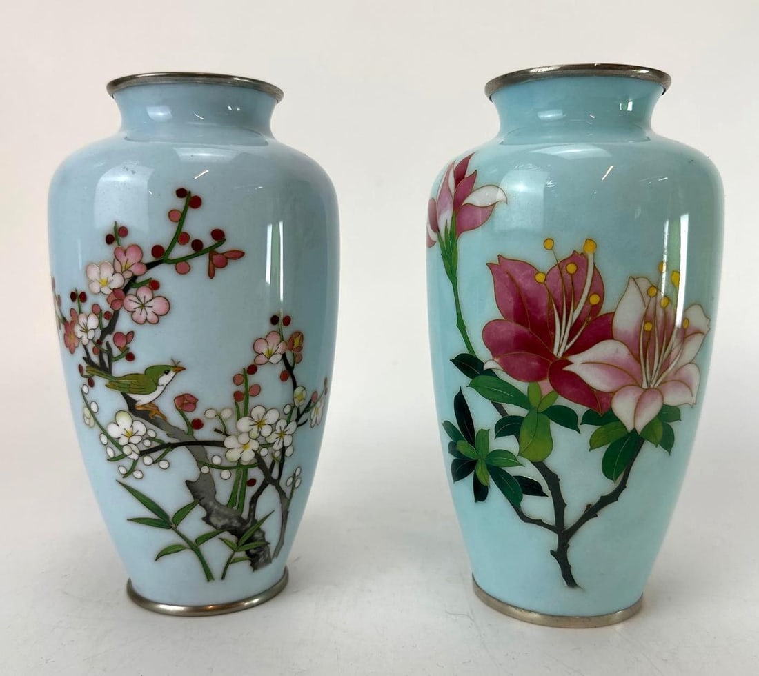 PAIR JAPANESE CLOISONNE ENAMEL VASES: A pair of vintage Japanese cloisonné enamel vases with light blue ground depicting a songbird on a flowering branch and blossoming lilies. Approximate Dimensions: 8" H X 4" Dia. Artist or Mak