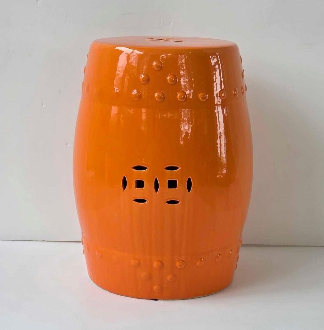 ORANGE GLAZED CERAMIC DRUM FORM GARDEN SEAT STOOL: Vibrant monochrome barrel shape earthenware porch stand decorated with raised bosses and pierced double coin motifs. Approximate Dimensions: 18"h x 12"dia Artist or Maker: Unknown Provenance: 