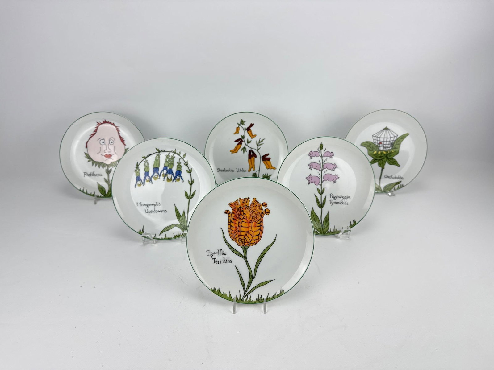 TASTE SETTER BY SIGMA WHIMSICAL NONSENSE BOTANICAL NOVELTY PLATES SET OF 6: Complete set of six ceramic dessert plates with green trim and humorous Edward Lear Nonsense Botany illustrations Approximate Dimensions: 7.5” Dia Artist or Maker: Taste Setter
